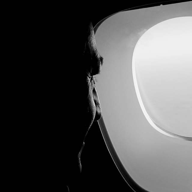 Silhouette of James Nixon looking out of an aircraft window from the inside